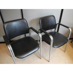 2 zwarte fauteuils met armleuningen en chroom onderstel